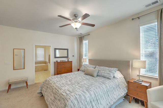 bedroom with visible vents, multiple windows, light carpet, and connected bathroom