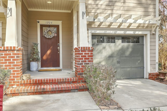 view of exterior entry with a garage, brick siding, and driveway