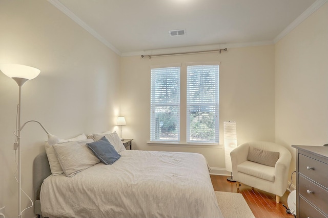 bedroom with crown molding, wood finished floors, and visible vents