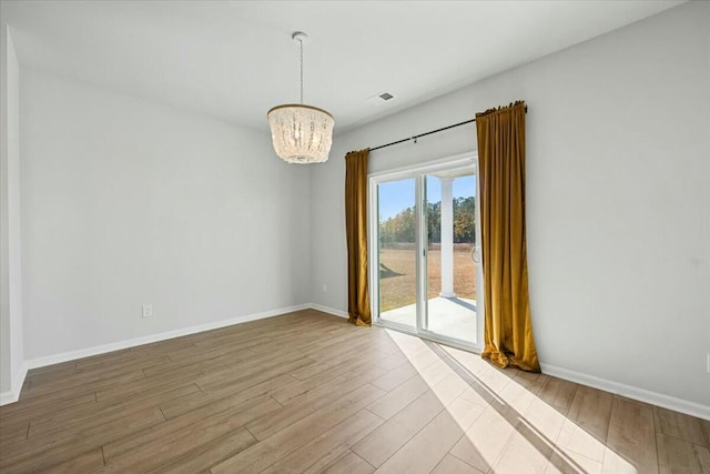 unfurnished room with light hardwood / wood-style flooring and a notable chandelier