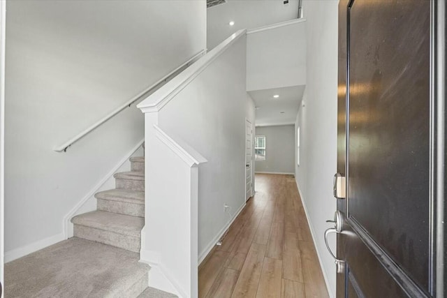 staircase with crown molding and wood-type flooring