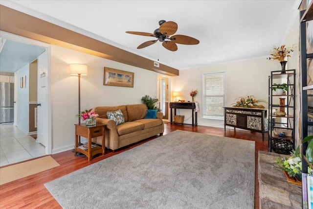 living room with ornamental molding, a ceiling fan, baseboards, and wood finished floors