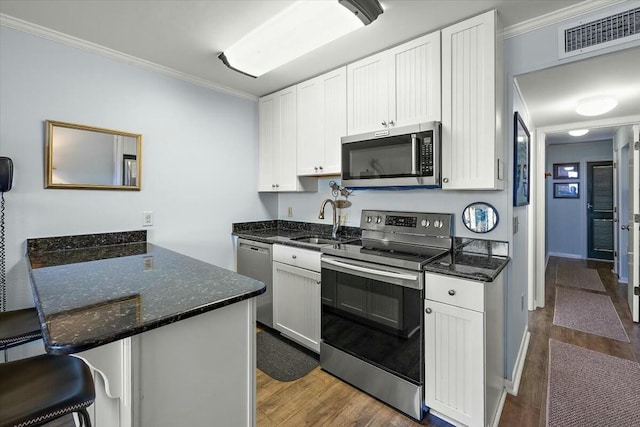 kitchen with a breakfast bar, visible vents, appliances with stainless steel finishes, white cabinetry, and a sink