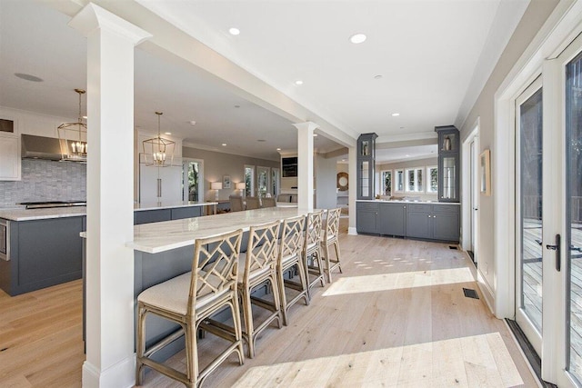 kitchen featuring tasteful backsplash, decorative columns, light hardwood / wood-style flooring, and pendant lighting