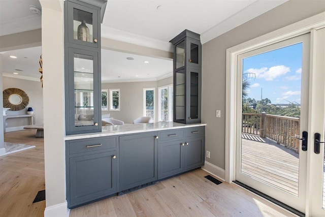 bar with crown molding, gray cabinets, and light hardwood / wood-style flooring