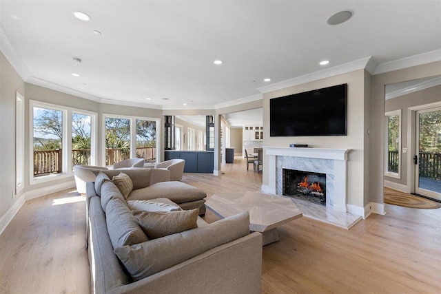 living room with crown molding, a high end fireplace, and light wood-type flooring