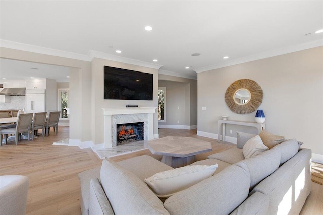 living room featuring ornamental molding, a premium fireplace, and light hardwood / wood-style floors