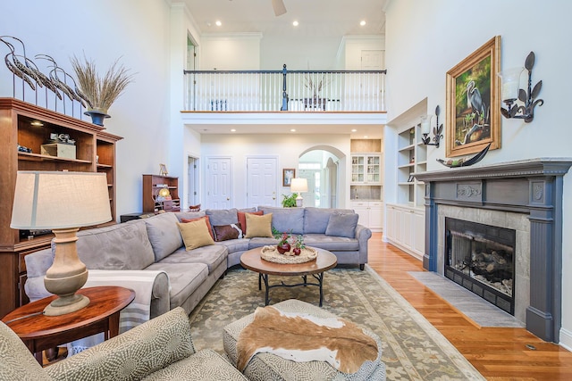 living area with built in shelves, light wood finished floors, recessed lighting, a fireplace, and arched walkways