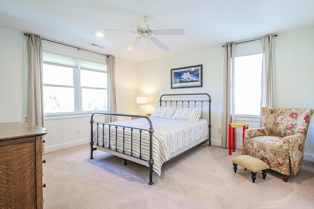 bedroom featuring visible vents, baseboards, light colored carpet, and a ceiling fan