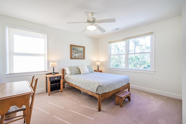 bedroom with visible vents, light colored carpet, baseboards, and ceiling fan