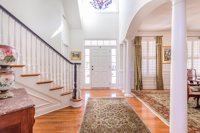 entrance foyer featuring stairs, decorative columns, wood finished floors, and a healthy amount of sunlight