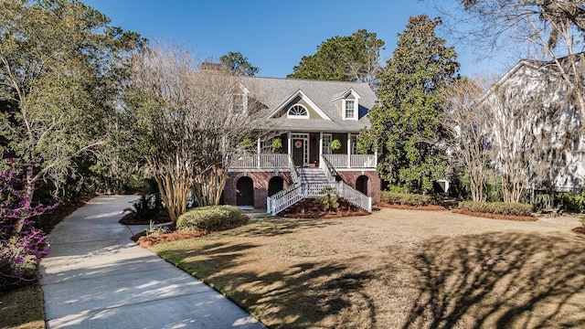 view of front of property featuring brick siding, a porch, stairs, and a front yard