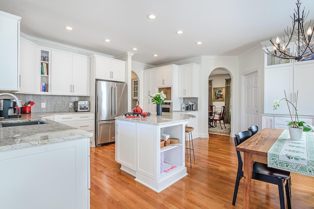 kitchen featuring arched walkways, appliances with stainless steel finishes, and open shelves