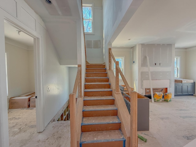 stairs with a wealth of natural light and ornamental molding