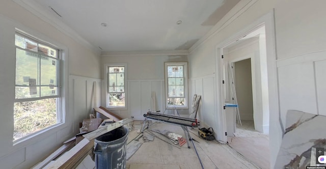 interior space with ornamental molding, wainscoting, and a decorative wall