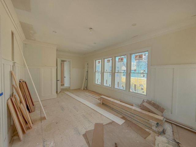 unfurnished room featuring a decorative wall, a wainscoted wall, and ornamental molding