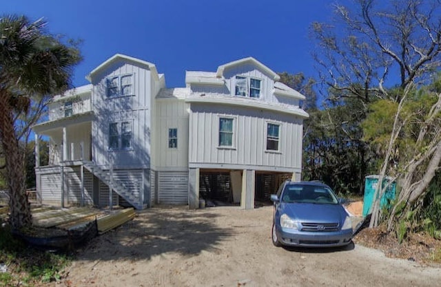 view of front of home featuring stairs, a carport, board and batten siding, and driveway