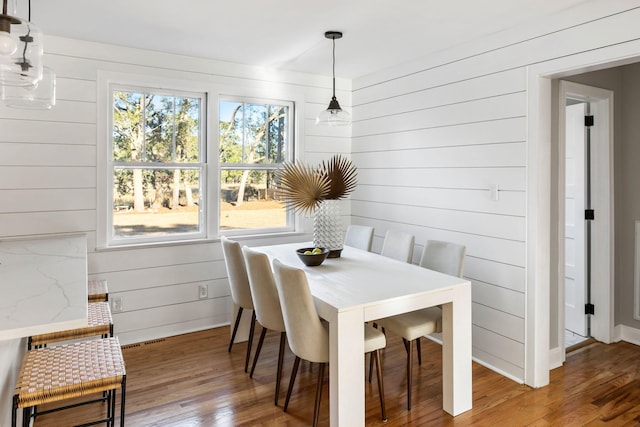 dining area featuring wooden walls and hardwood / wood-style flooring