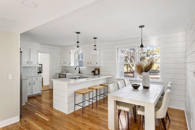 kitchen with white cabinets, decorative backsplash, a breakfast bar, and kitchen peninsula