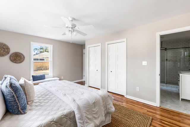 bedroom with ceiling fan, light wood-type flooring, ensuite bathroom, and two closets