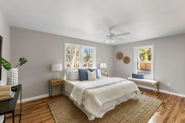 bedroom with multiple windows, ceiling fan, and hardwood / wood-style flooring