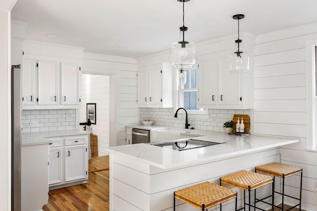 kitchen with a kitchen breakfast bar, kitchen peninsula, hardwood / wood-style flooring, decorative light fixtures, and white cabinetry