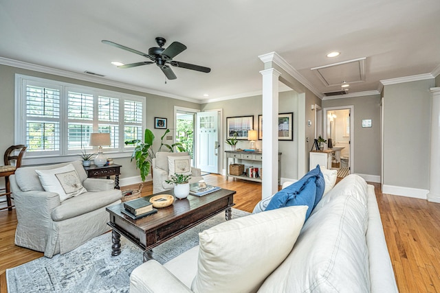 living room with visible vents, ornamental molding, attic access, light wood-type flooring, and baseboards