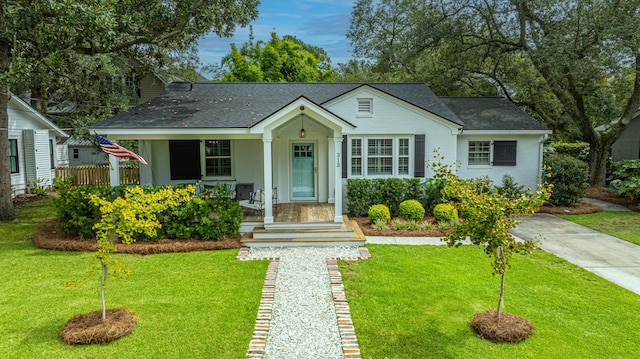 view of front of property featuring a porch, a shingled roof, and a front lawn