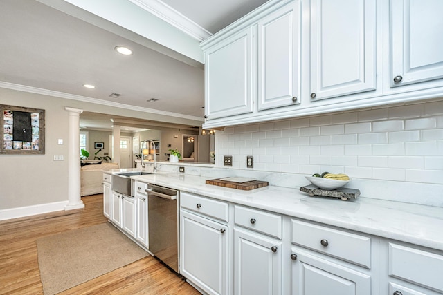 kitchen featuring ornate columns, ornamental molding, stainless steel dishwasher, and a sink