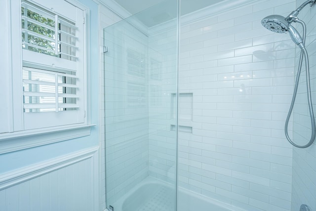 bathroom featuring shower / bath combination with glass door, wainscoting, and crown molding