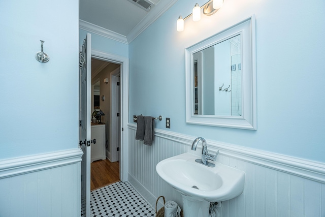 bathroom featuring crown molding, a wainscoted wall, a sink, and visible vents