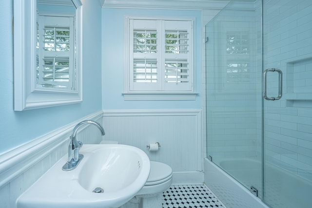 full bathroom featuring bath / shower combo with glass door, toilet, wainscoting, a sink, and tile patterned floors