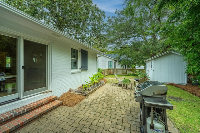 view of patio featuring a storage unit, fence, area for grilling, and an outdoor structure