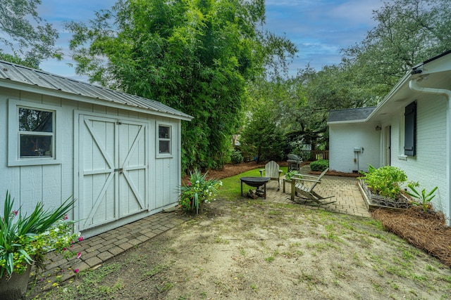 view of yard featuring an outbuilding, a shed, an outdoor fire pit, and a patio area