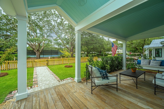 wooden deck featuring an outdoor hangout area, a lawn, and fence