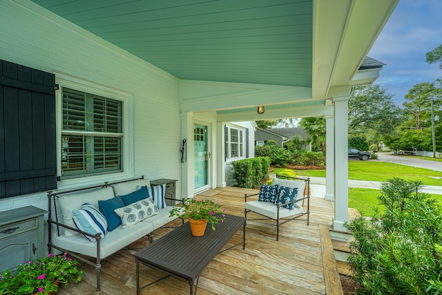 wooden deck with covered porch and a lawn