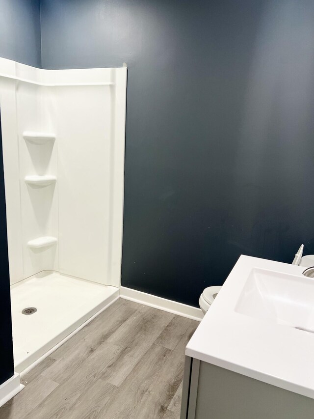 bathroom with vanity, toilet, hardwood / wood-style flooring, and a shower