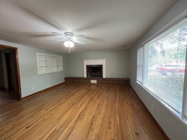 unfurnished living room with a fireplace, ceiling fan, and light hardwood / wood-style flooring