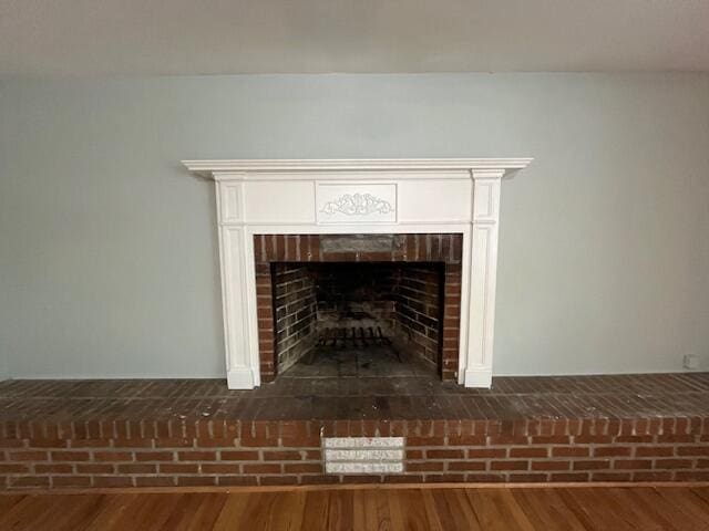 interior details with wood-type flooring and a brick fireplace