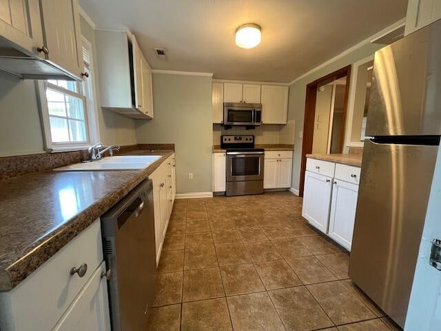 kitchen with dark tile patterned flooring, white cabinets, stainless steel appliances, and sink