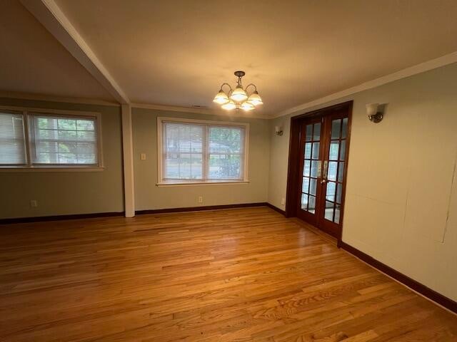 unfurnished dining area featuring light wood-type flooring, a wealth of natural light, french doors, and a chandelier