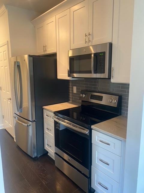 kitchen with white cabinets, tasteful backsplash, stainless steel appliances, light stone countertops, and dark hardwood / wood-style flooring