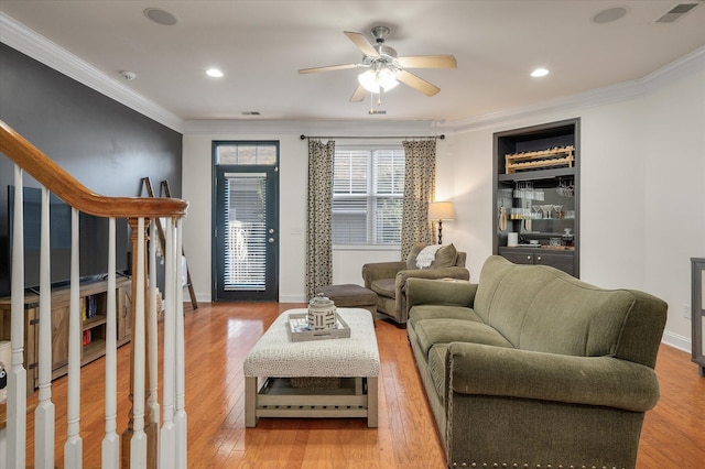 living room with crown molding, wood finished floors, and visible vents