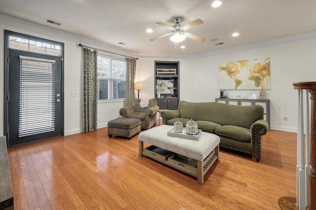 living area featuring visible vents, crown molding, baseboards, ceiling fan, and light wood-style flooring