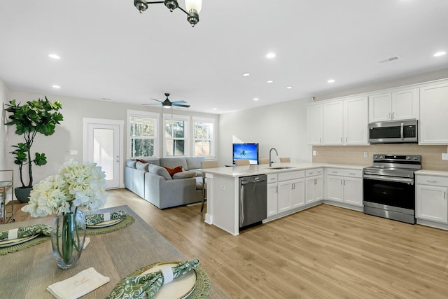 kitchen with sink, kitchen peninsula, white cabinets, and stainless steel appliances