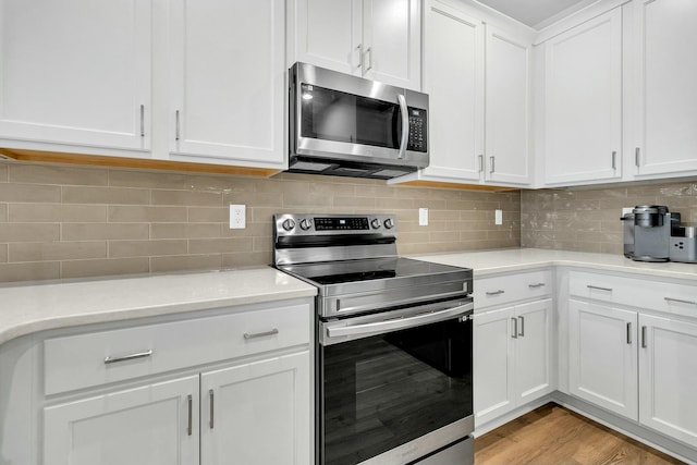 kitchen featuring light hardwood / wood-style flooring, decorative backsplash, stainless steel appliances, and white cabinetry