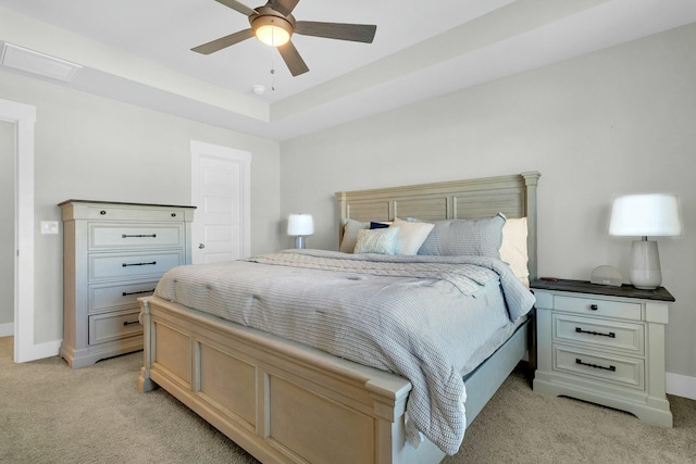 carpeted bedroom featuring ceiling fan and a tray ceiling