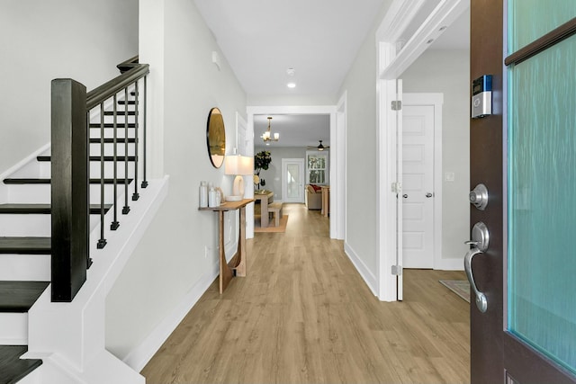 entryway featuring ceiling fan with notable chandelier and light hardwood / wood-style floors