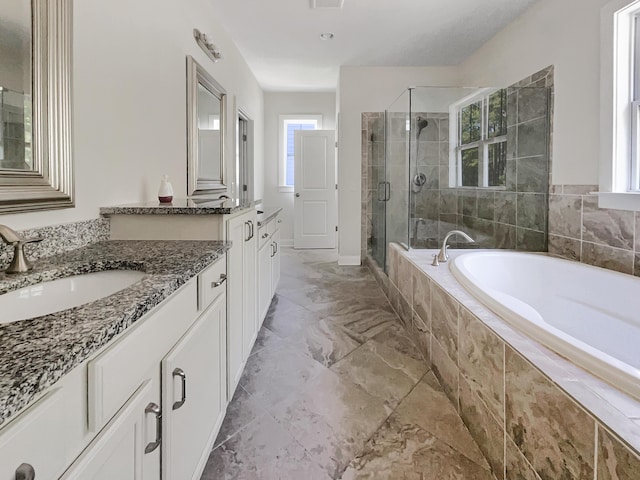 full bath featuring a garden tub, a stall shower, two vanities, a sink, and marble finish floor