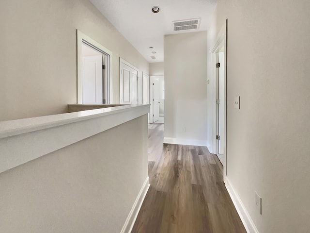 corridor with visible vents, dark wood-style flooring, and baseboards